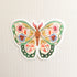 sticker of an illustrated green butterfly with flowers in its wings on a linen background