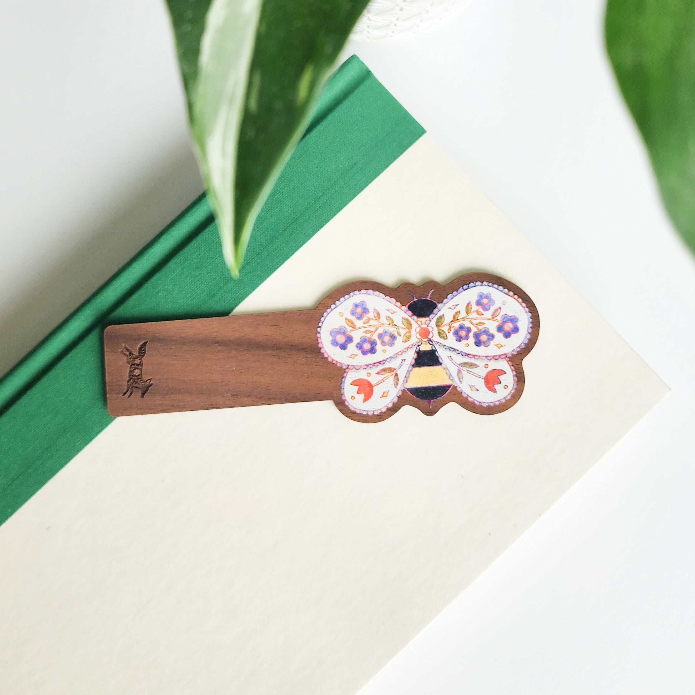 floral bee bookmark on a green and white book on a white background with leaves