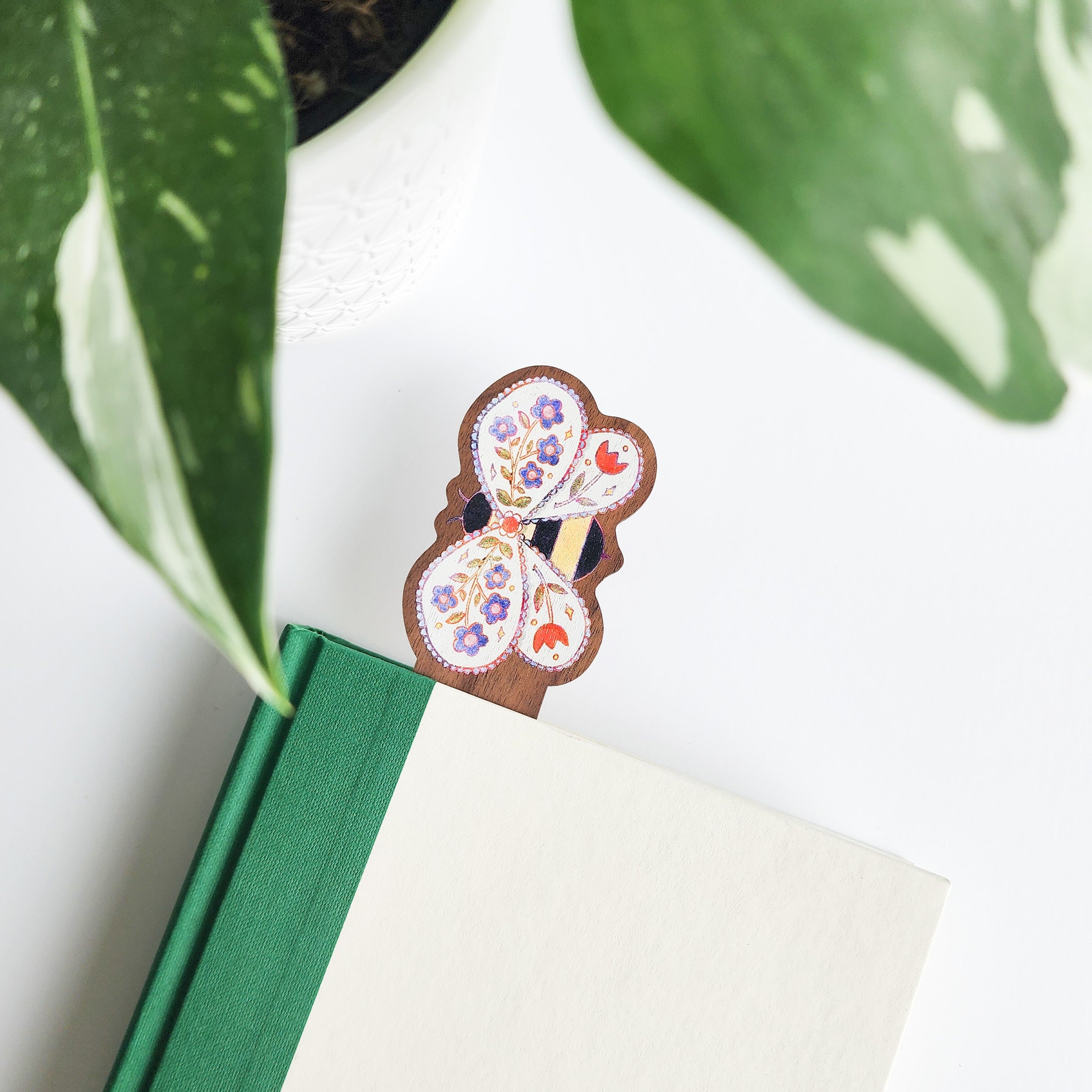 floral bee bookmark in a green and white book on a white background with leaves
