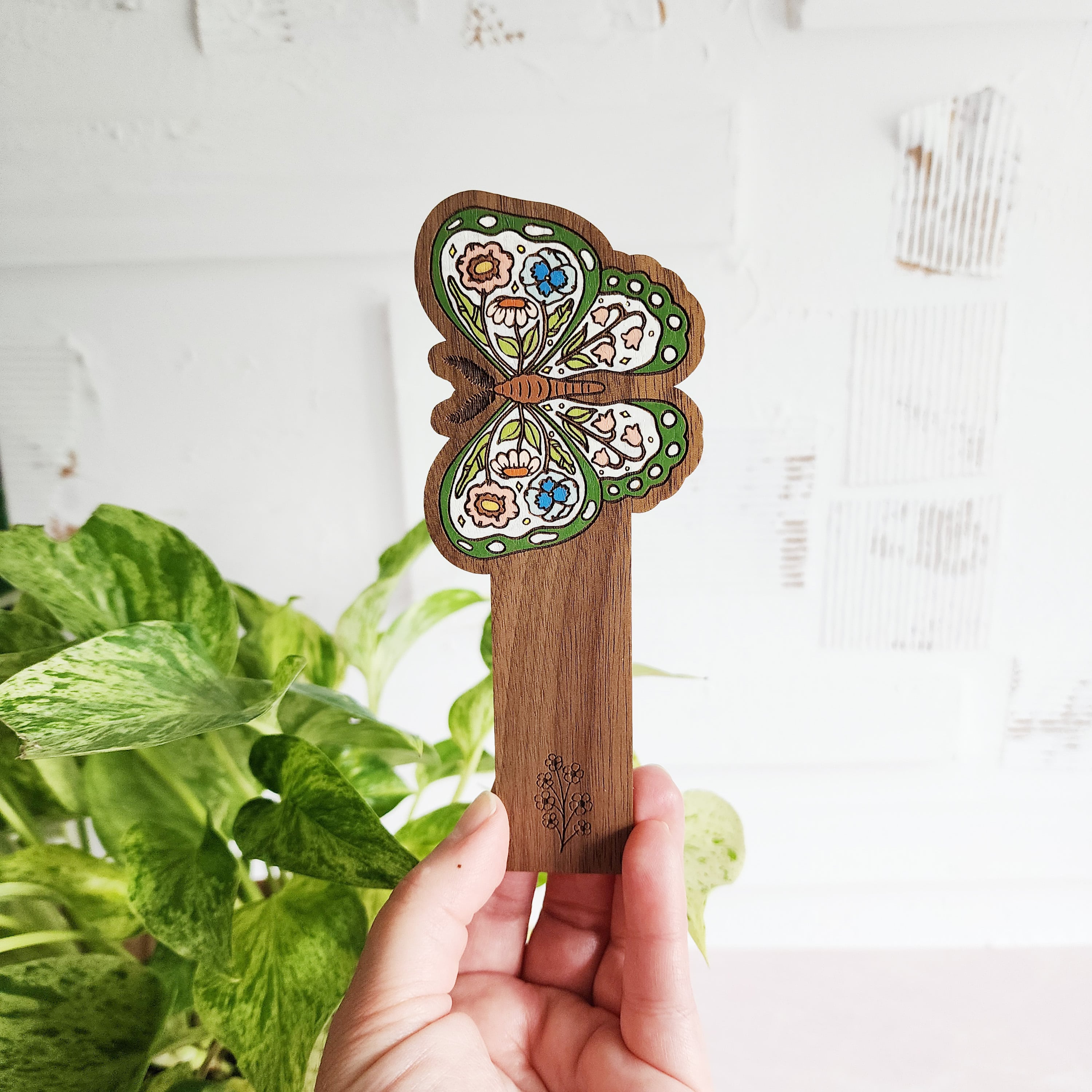 butterfly bookmark held in front of a plant