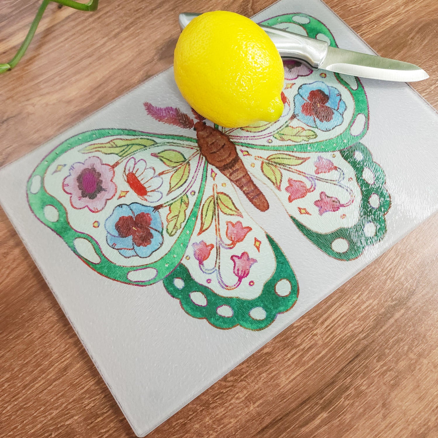 floral butterfly cutting board with a lemon and knife on it