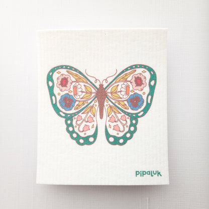 swedish dishcloth on a white background with a green floral butterfly design printed on it and a Pipaluk logo in the bottom right corner