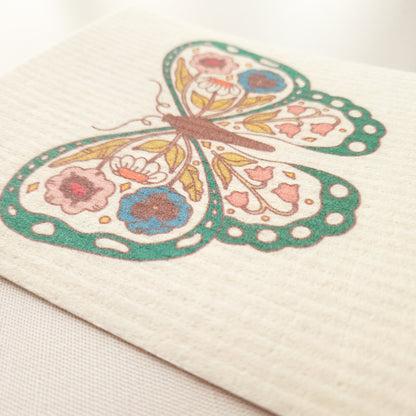 close up image of a swedish dishcloth with a green floral butterfly design showing the texture of the cloth