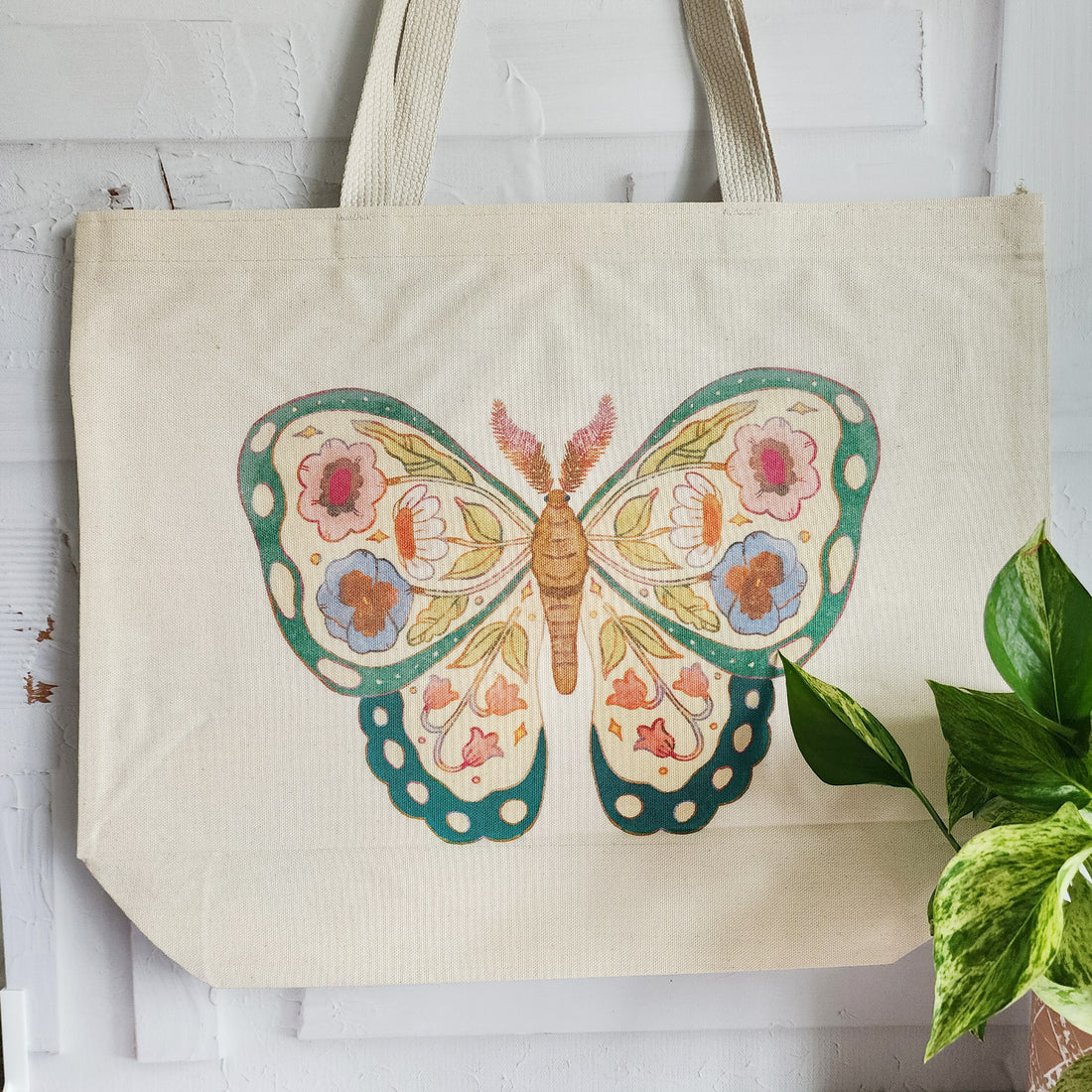 tote bag with a floral butterfly design hanging on a wall