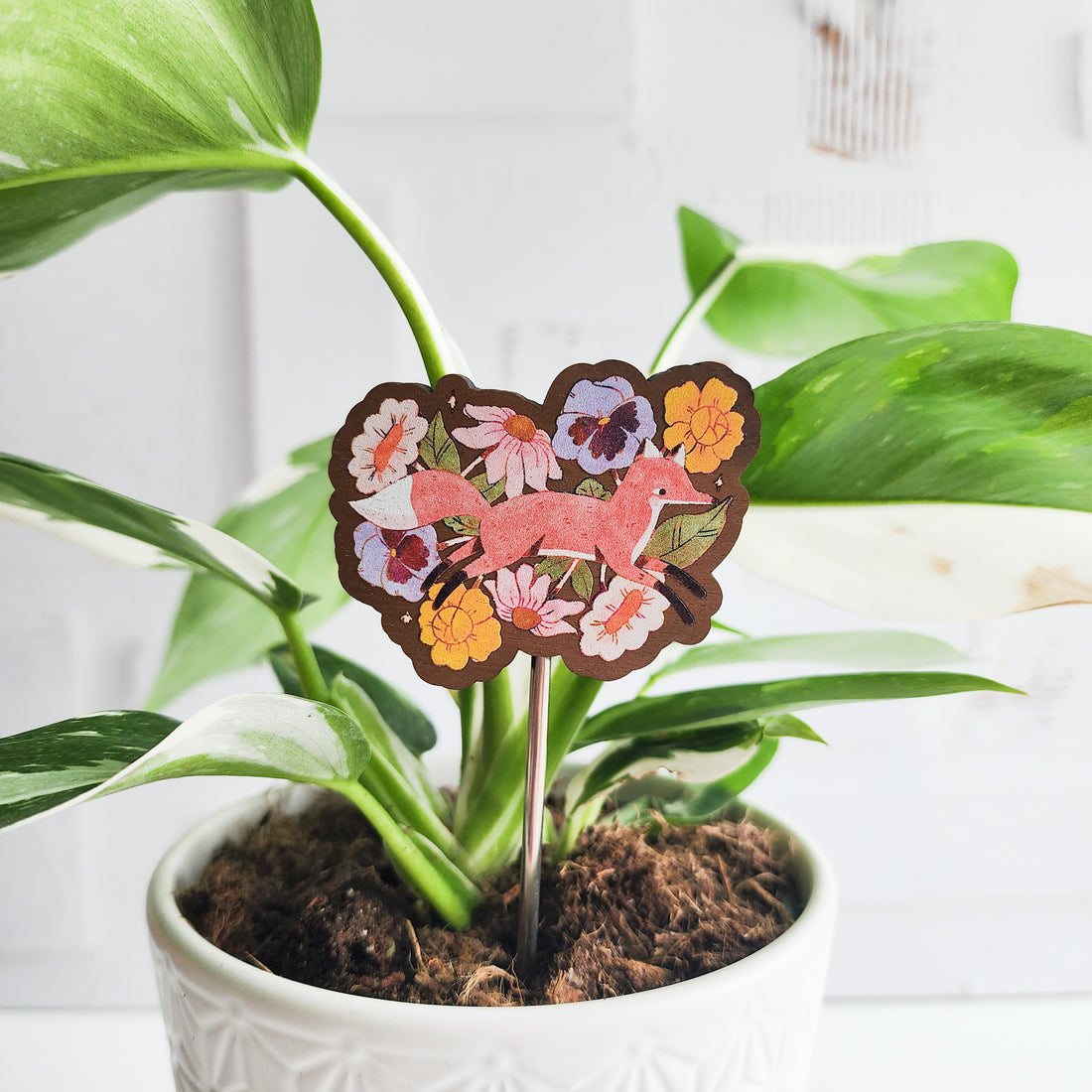 Decorative plant stake with a fox design in a potted plant on a white background