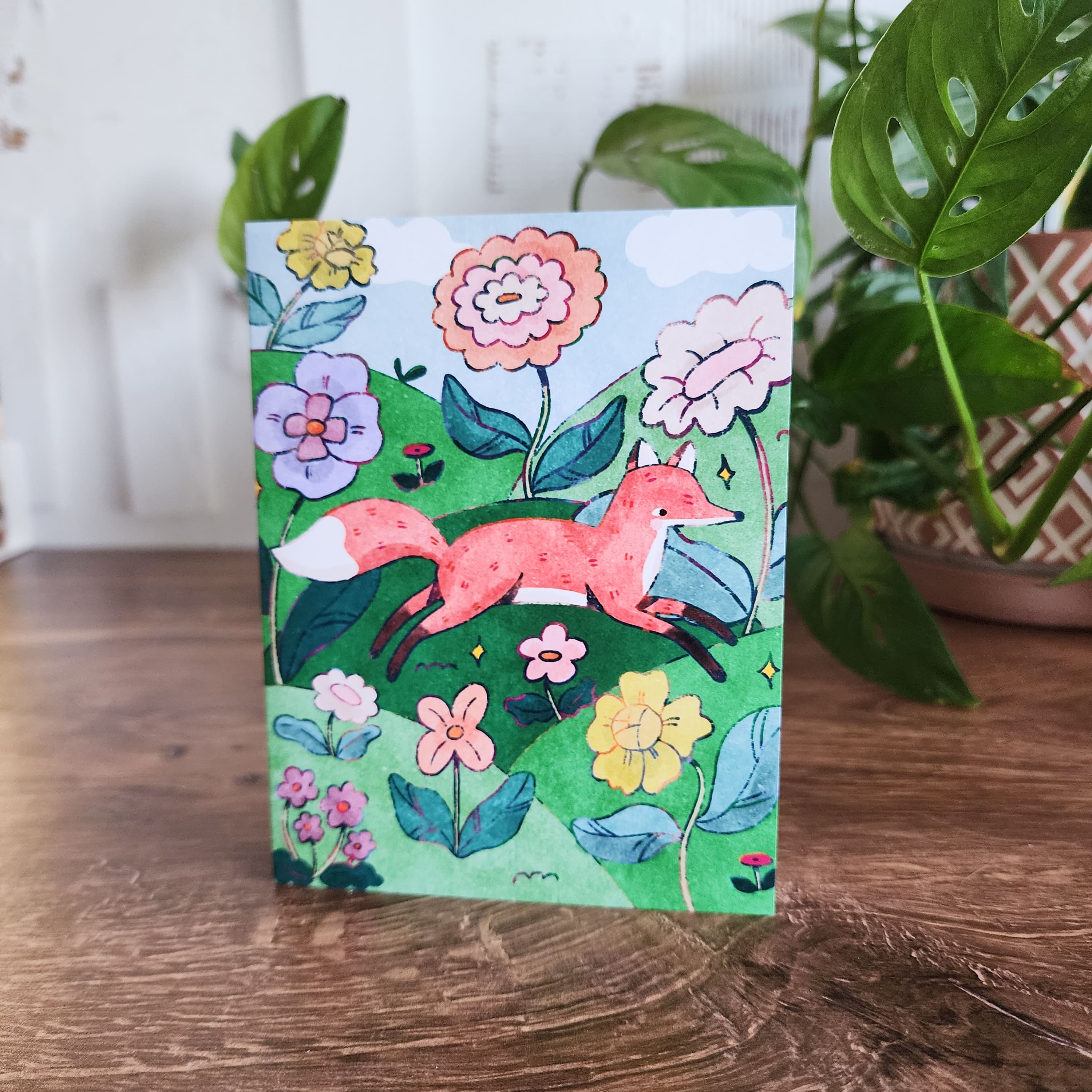 gretting card with a fox illustration sitting in front of a plant