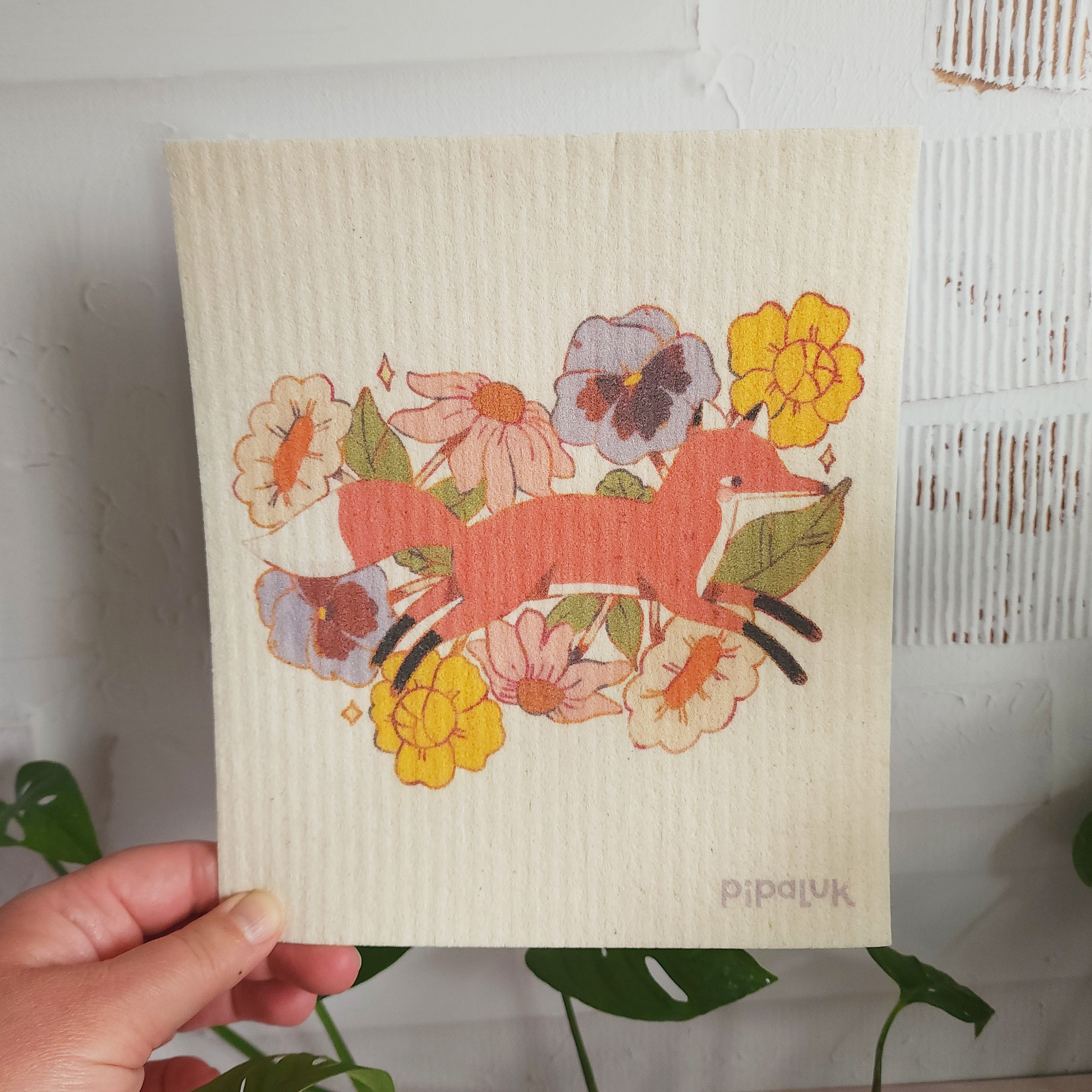 fox in blooms dishcloth held in a hand against a white background