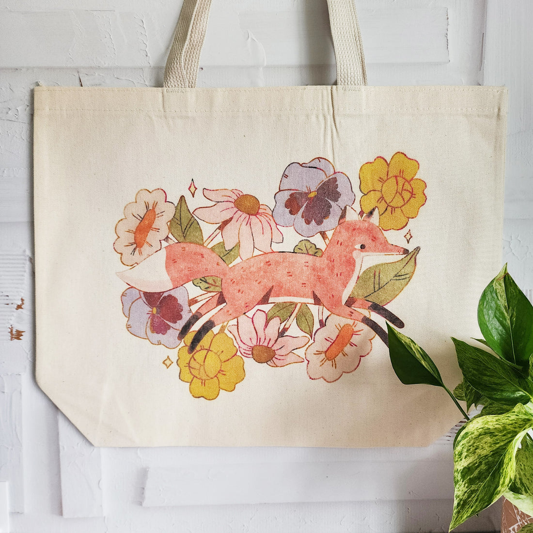 hanging tote bag with a design of a fox jumping through blooming flowers