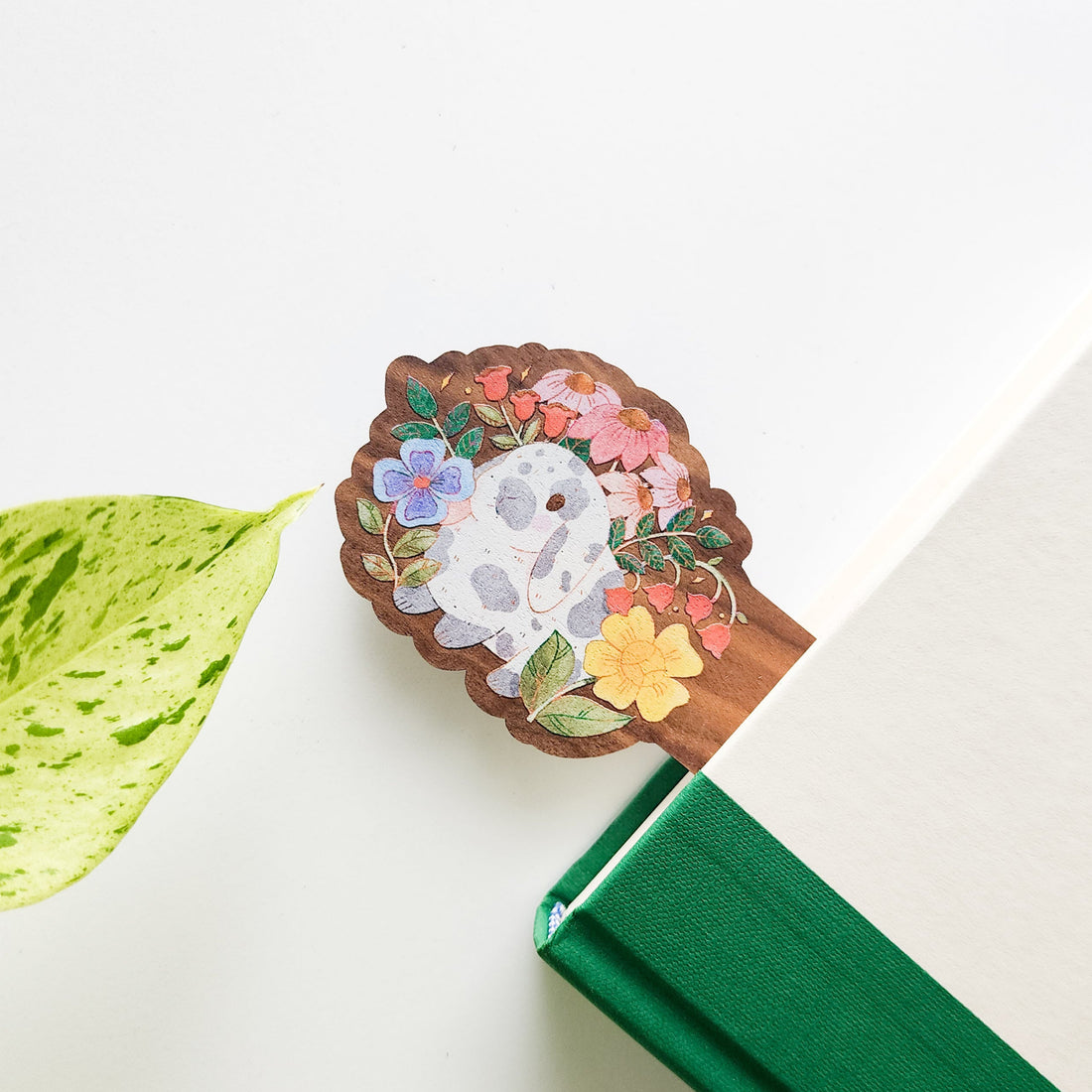 Decorative wooden bookmark with floral design and rabbit on a green book