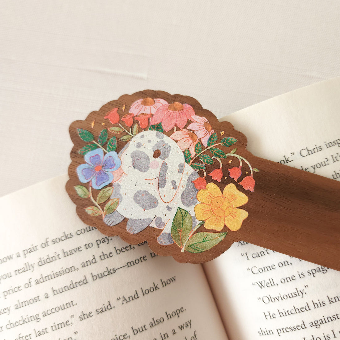 wooden bookmark with an illustration of a rabbit surrounded by flowers sitting on an open book