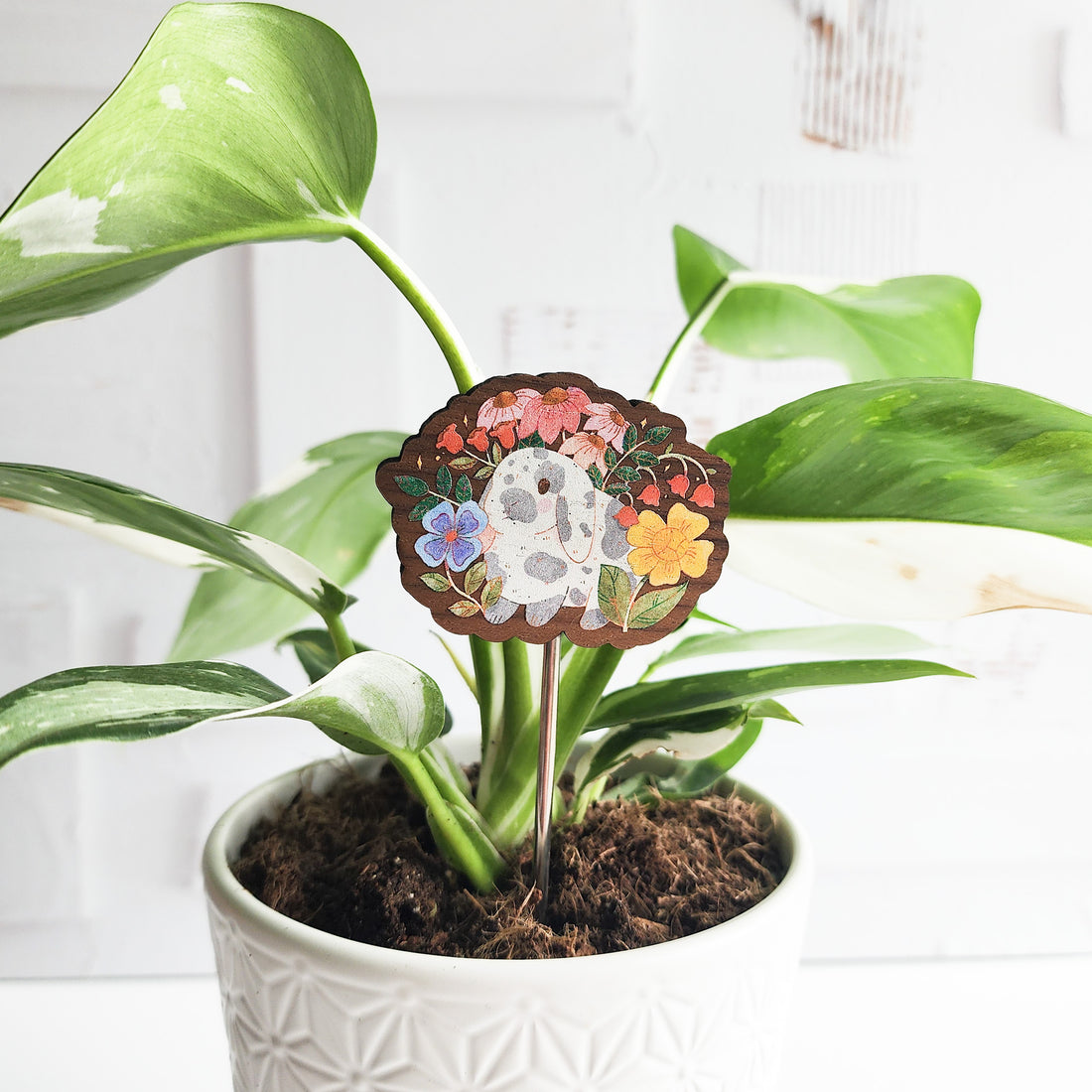 Decorative plant stake with a rabbit floral design in a pot against a white background