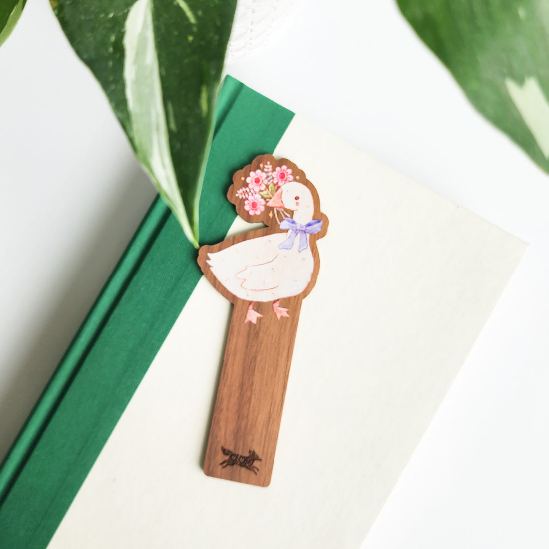 decorative goose bookmark on a green and white book on a white background with leaves