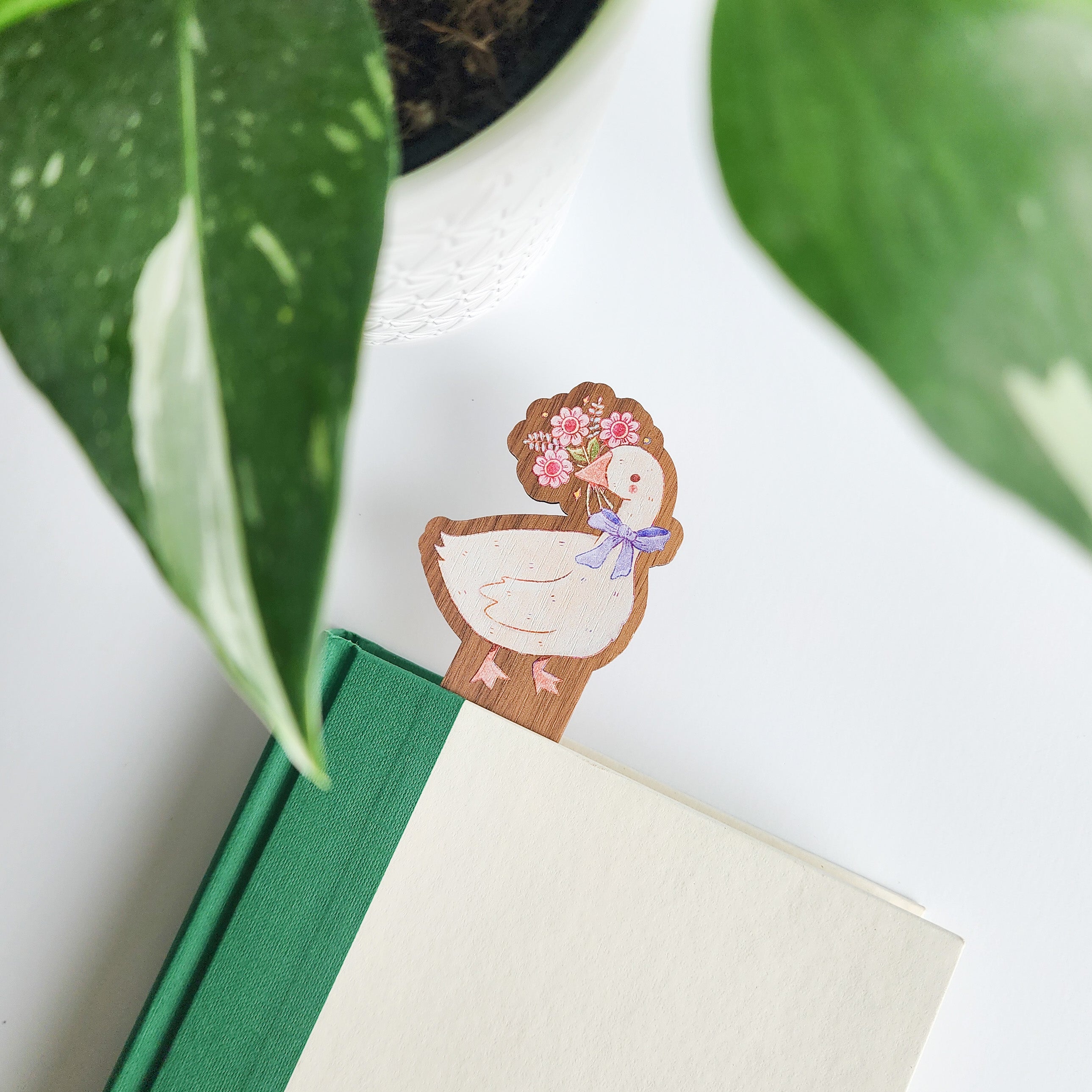 decorative goose bookmark inside of a book on a white background with leaves