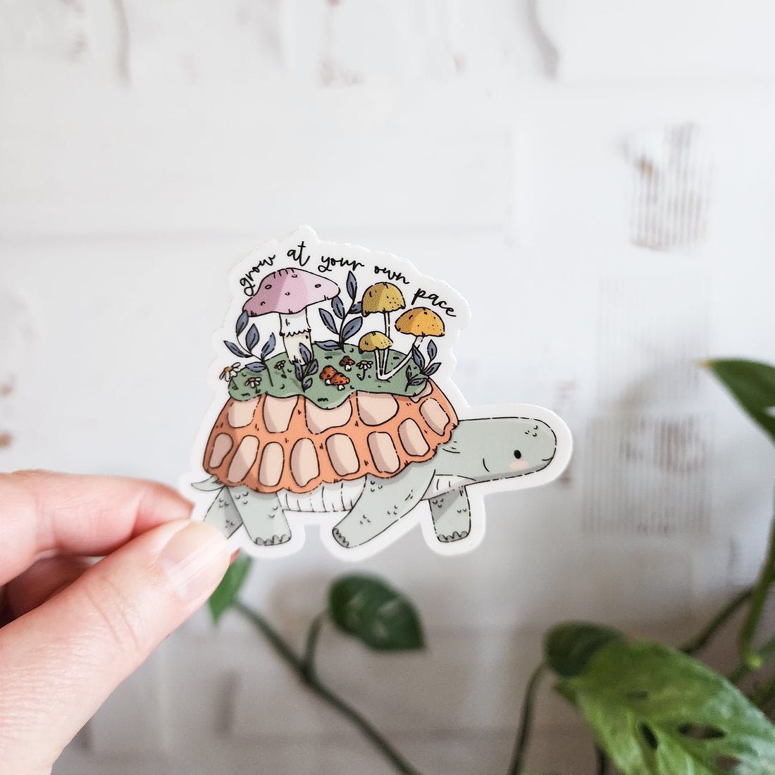 grow at your own pace turtle sticker held in a hand