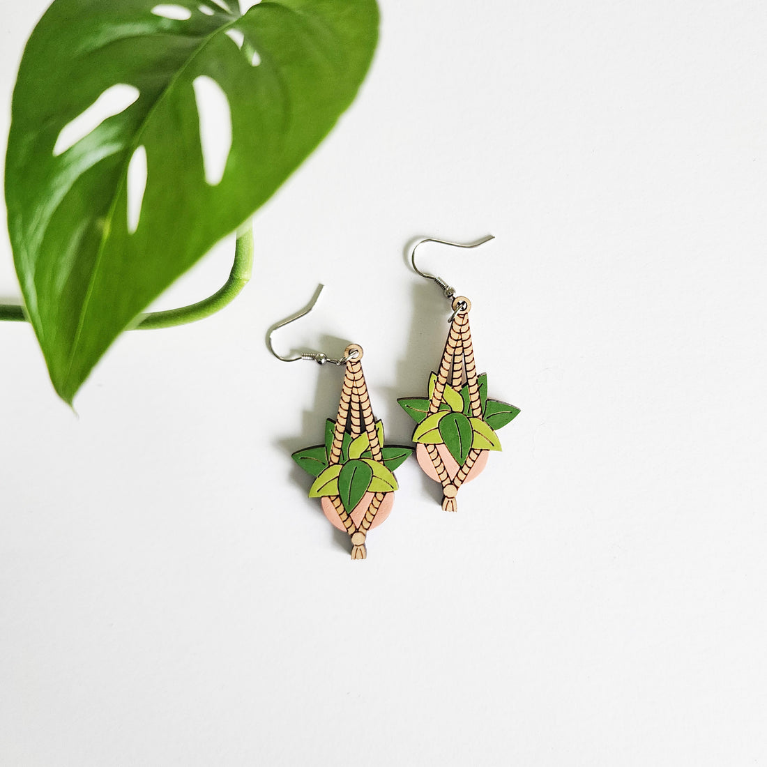 pair of hanging planter earrings on a white background with a leaf