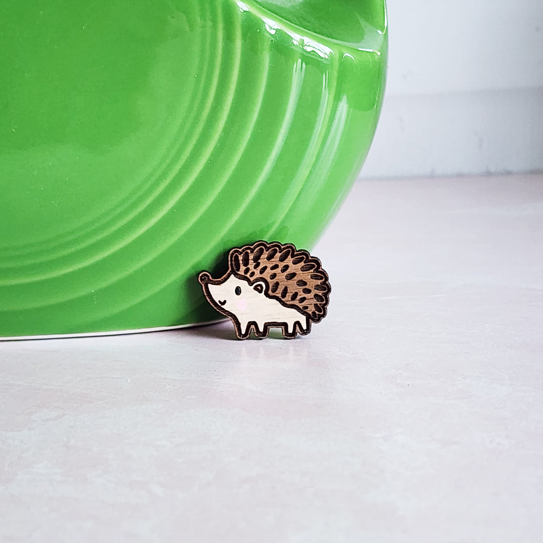 hedgehog pin sitting in front of a green vase