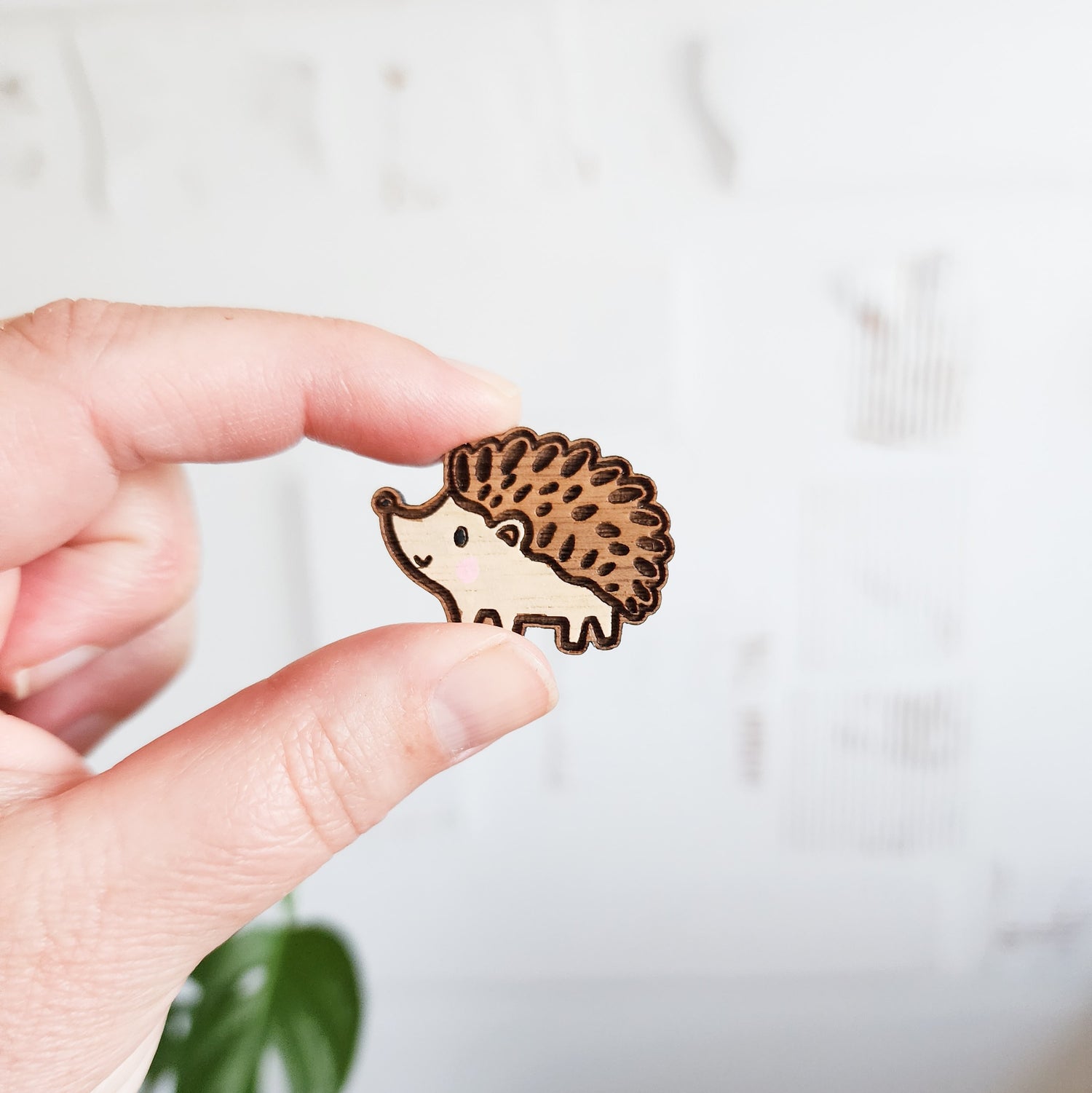 brown and cream hedgehog pin held between two fingers