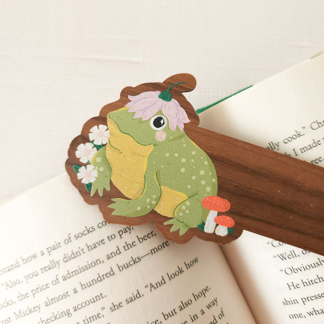 wooden bookmark with a frog illustration on an open book