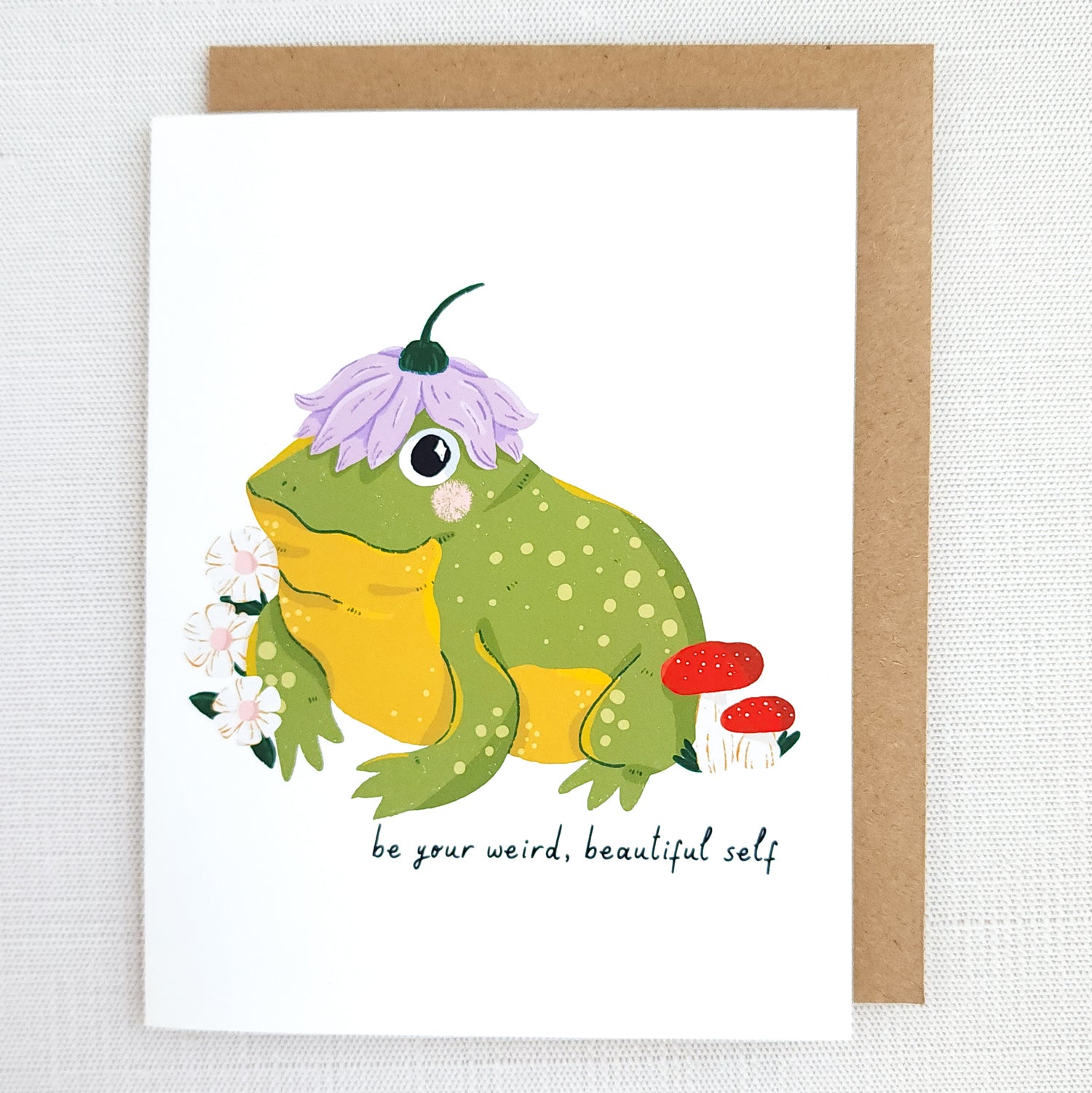 Greeting card with a frog illustration and text be your weird beautiful self on a white background
