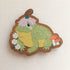 wooden magnet with an illustration of a happy toad wearing a flower a hat on a linen background