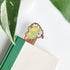 toad bookmark inside a green and white book on a white background with green leaves