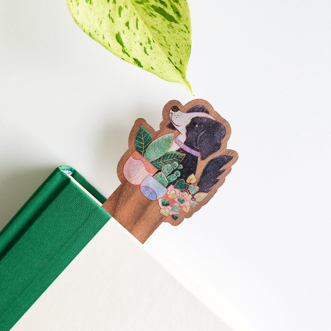 Wooden bookmark with dog and houseplants on a green book