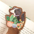 wooden bookmark with an illustration of a dog and plants sitting on an open book