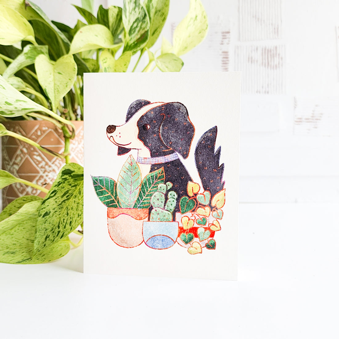 Card with a dog illustration surrounded by plants on a white background
