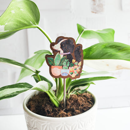 decorative dog plant stake in a potted plant against a white brick background