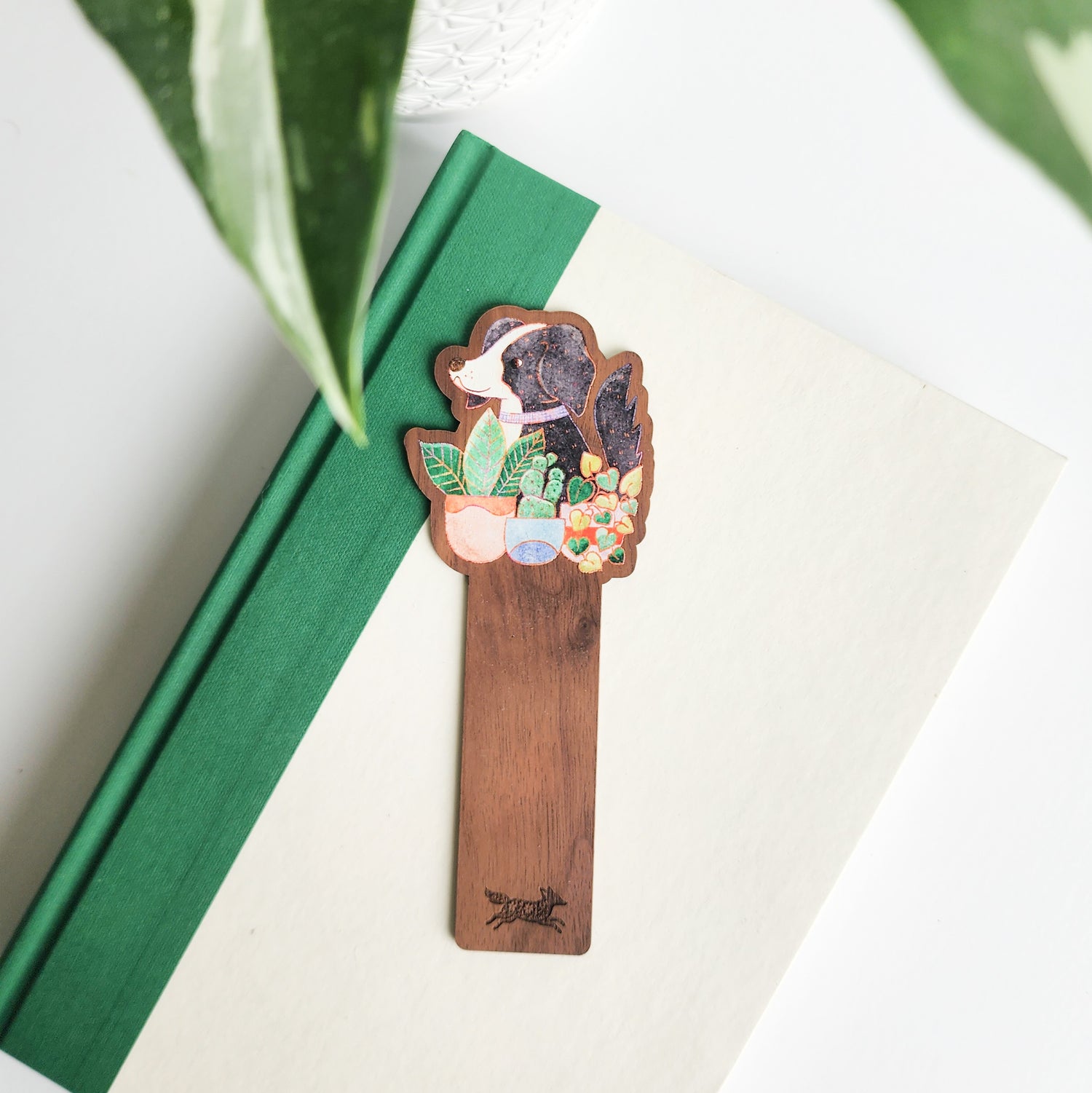 dog and houseplants bookmark on a green and white book on a white background with leaves