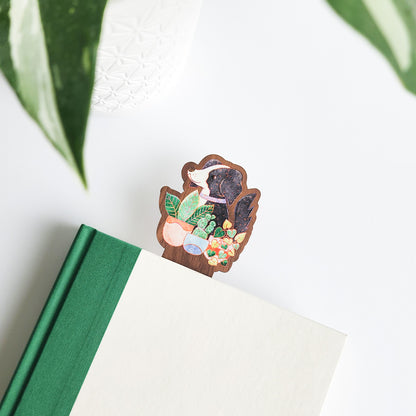 dog with houseplants bookmark inside a green and white book on a white background with leaves