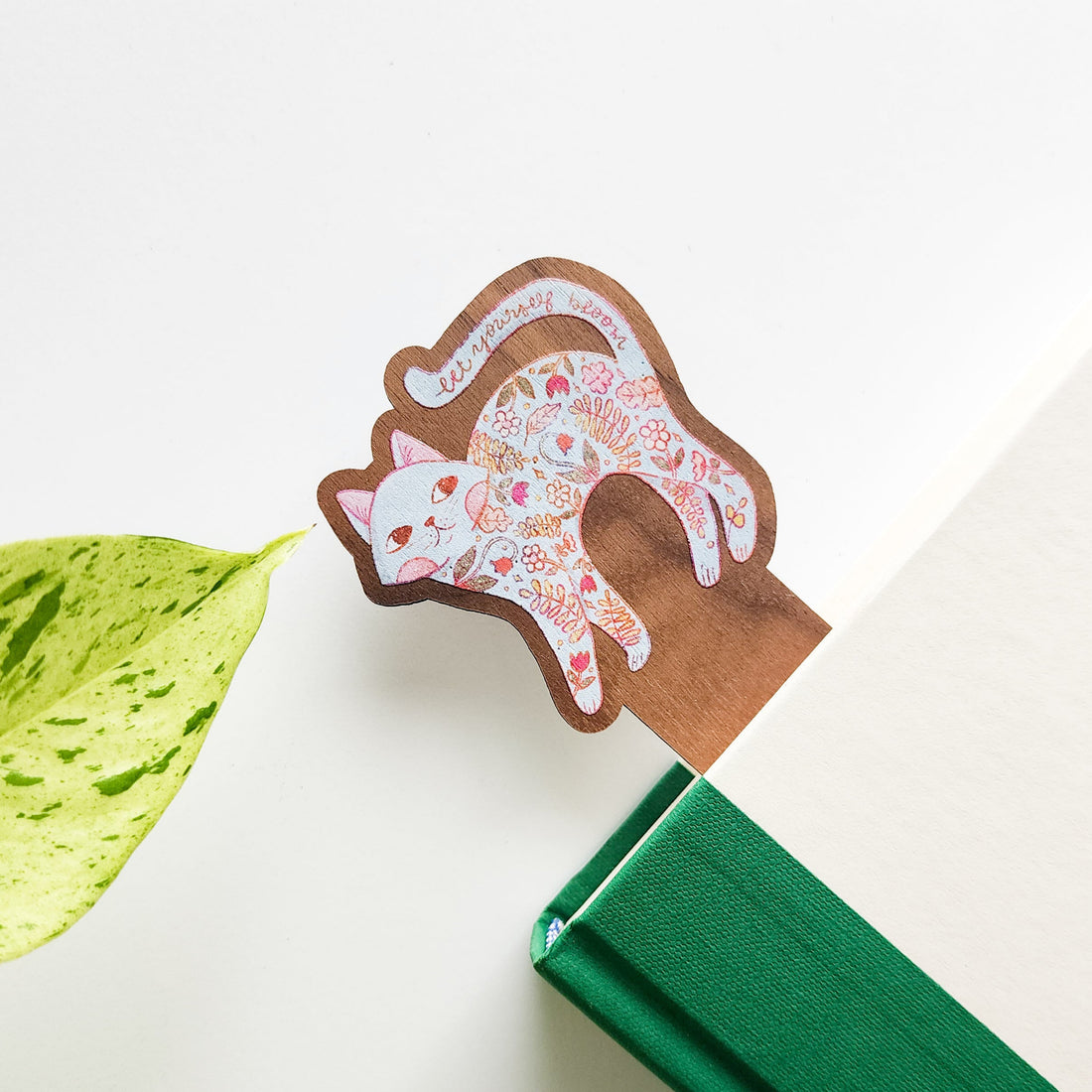 Decorative bookmark with floral patterned cat on a green book