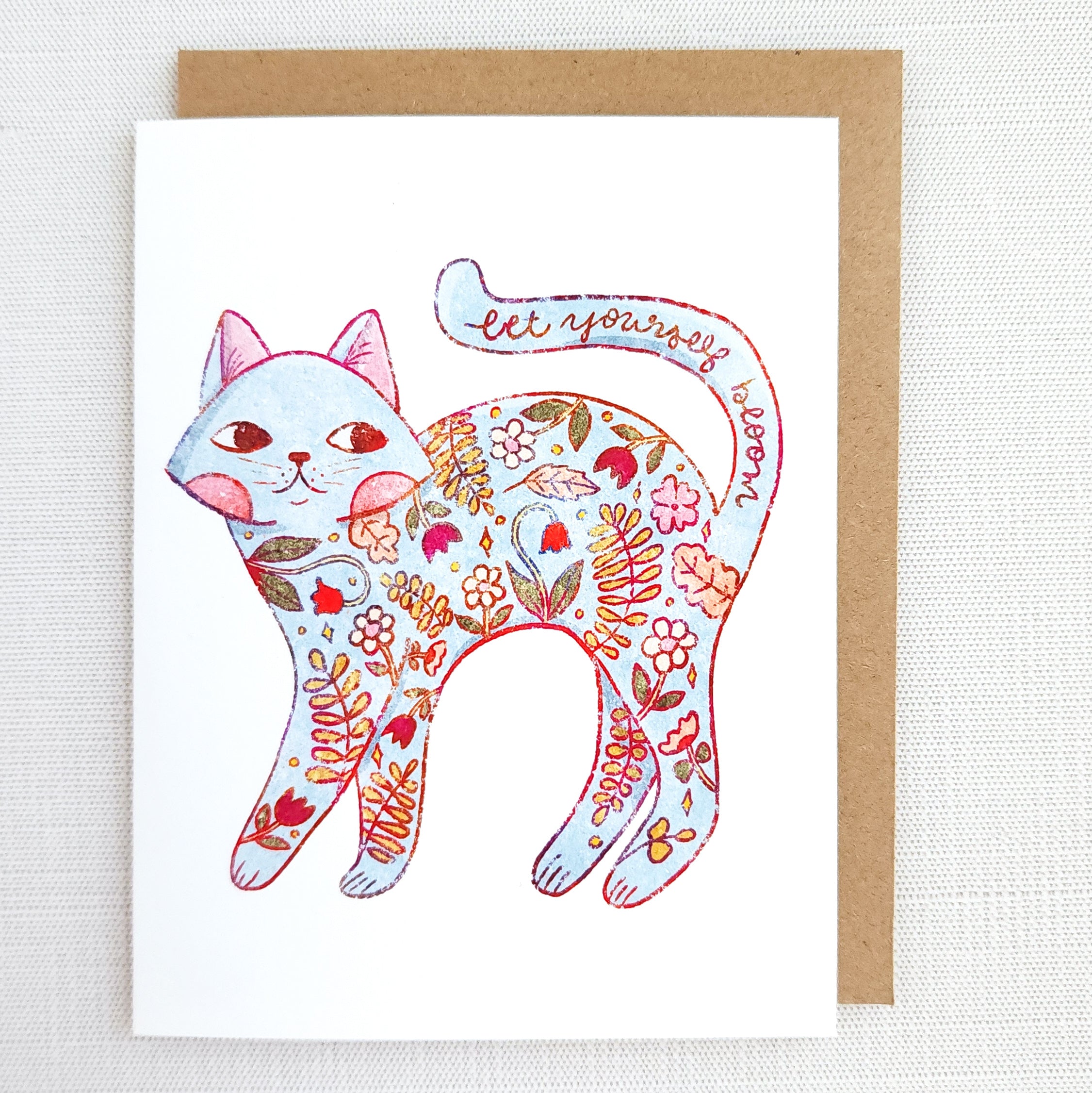 Greeting card with a colorful cat illustration and floral patterns on a white background.