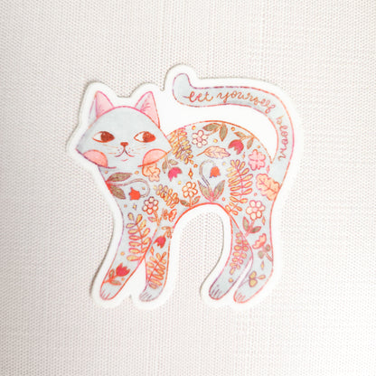 sticker of a floral cat with the words let yourself bloom on a linen background