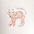 sticker of a floral cat with the words let yourself bloom on a linen background