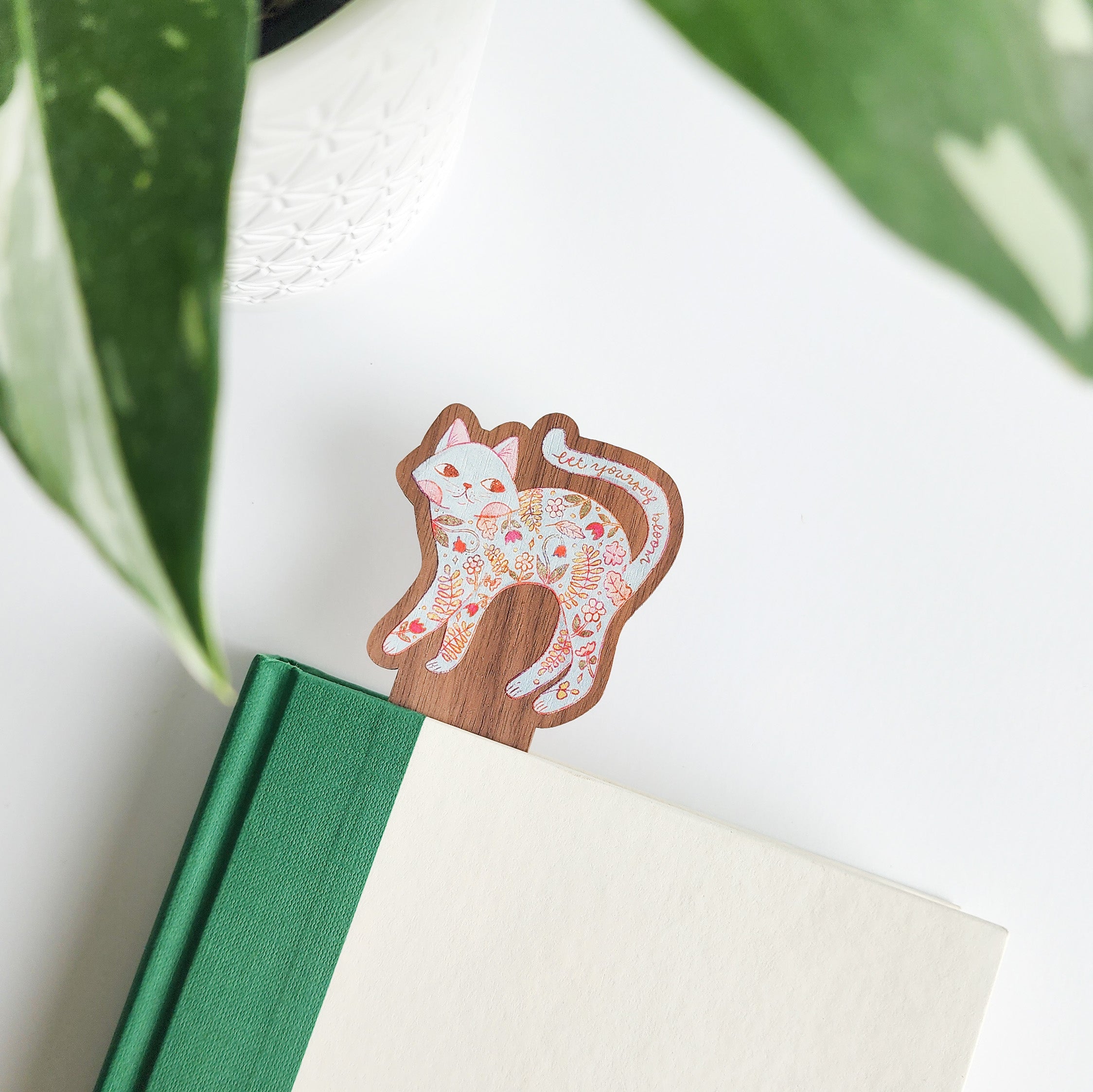 Wooden bookmark with floral cat design in a green and white book