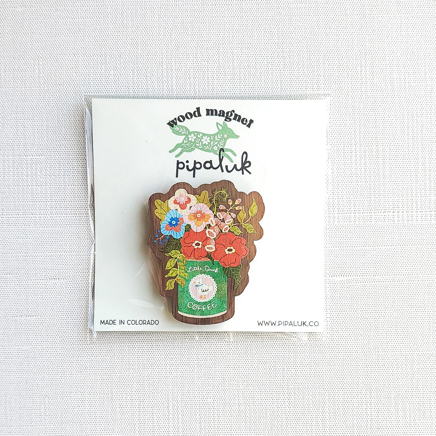Wooden magnet with an illustrated Little Duck Coffee can repurposed as a vase, filled with cheerful pink, yellow, and blue flowers in Pipaluk branded packaging on a neutral background
