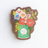 Wooden magnet with an illustrated Little Duck Coffee can repurposed as a vase, filled with cheerful pink, yellow, and blue flowers on a neutral background