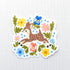 Vinyl sticker featuring a sweet spotted fawn dancing among colorful wildflowers, with pink, yellow, blue, and green floral details on a neutral background.
