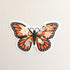 sticker with an illustration of a monarch butterfly with flowers in its wings on a linen background