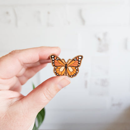 monarch butterfly pin held between two fingers