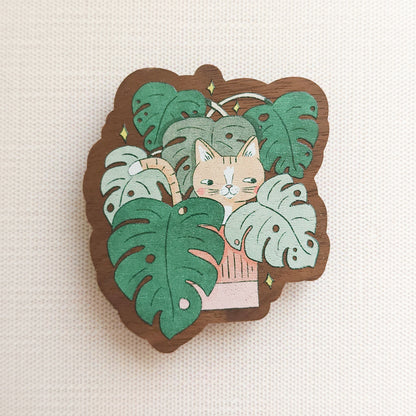 wooden magnet with an image of a cat in a monstera plant on a linen background
