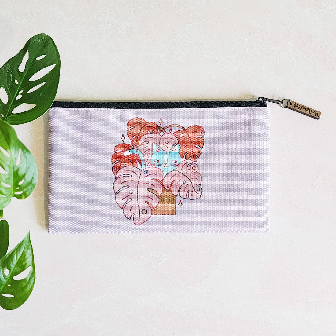 purple zipper pouch with the design of a cat sitting in a monstera plant