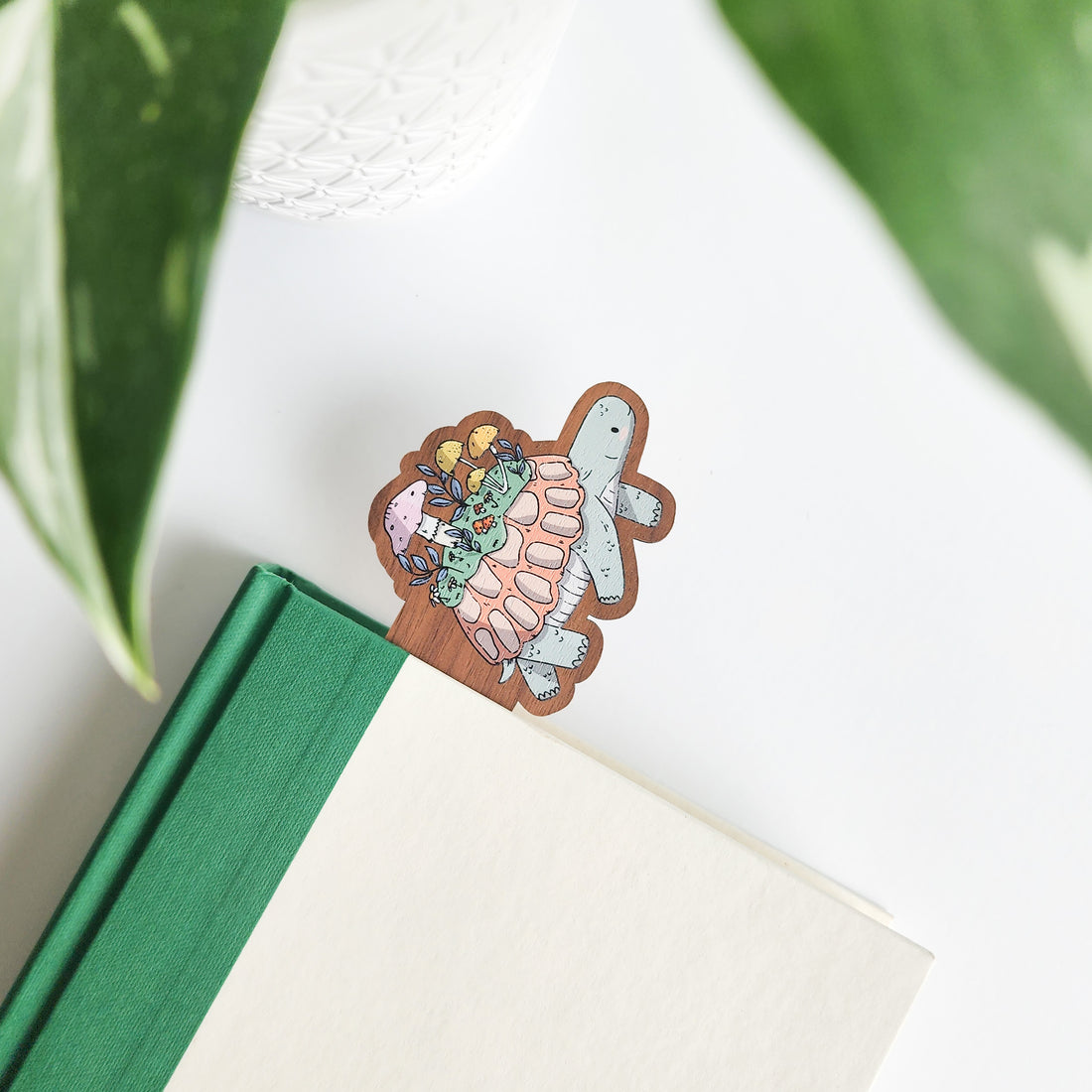 Decorative turtle-shaped bookmark on a book with green leaves in the background