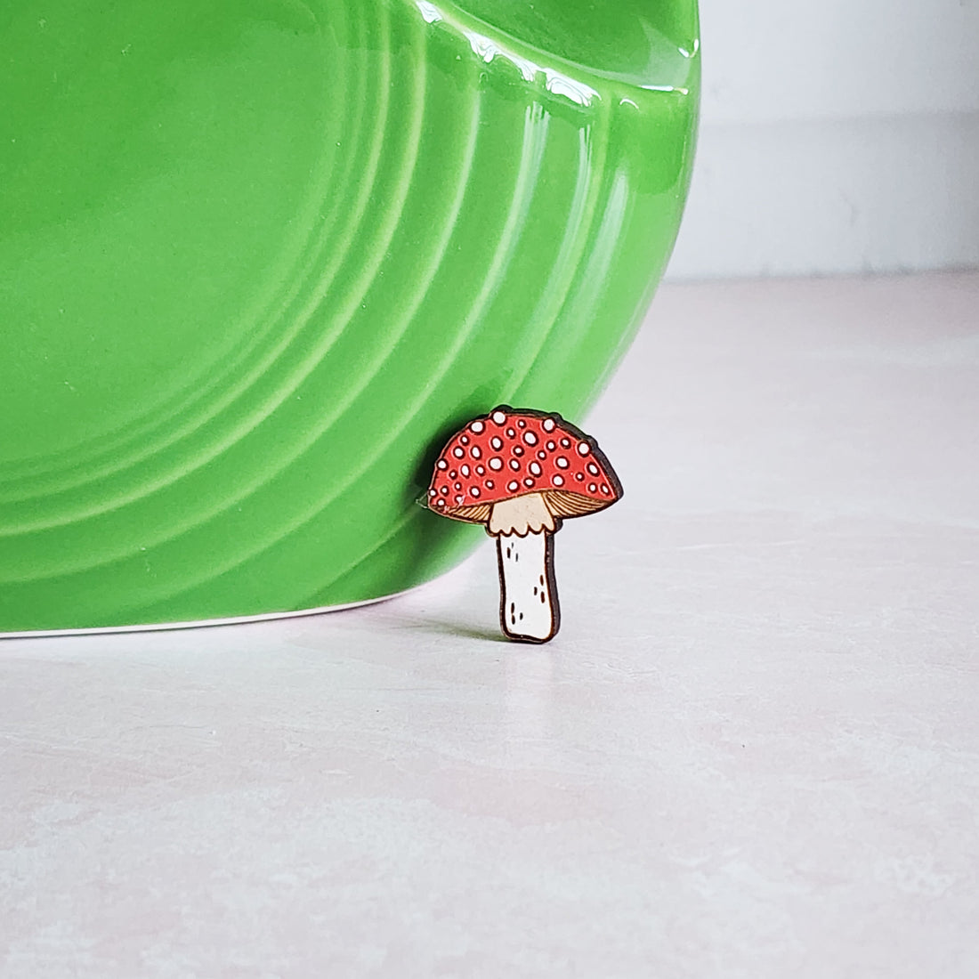 red and white dotted mushroom pin sitting inf ront of a green vase