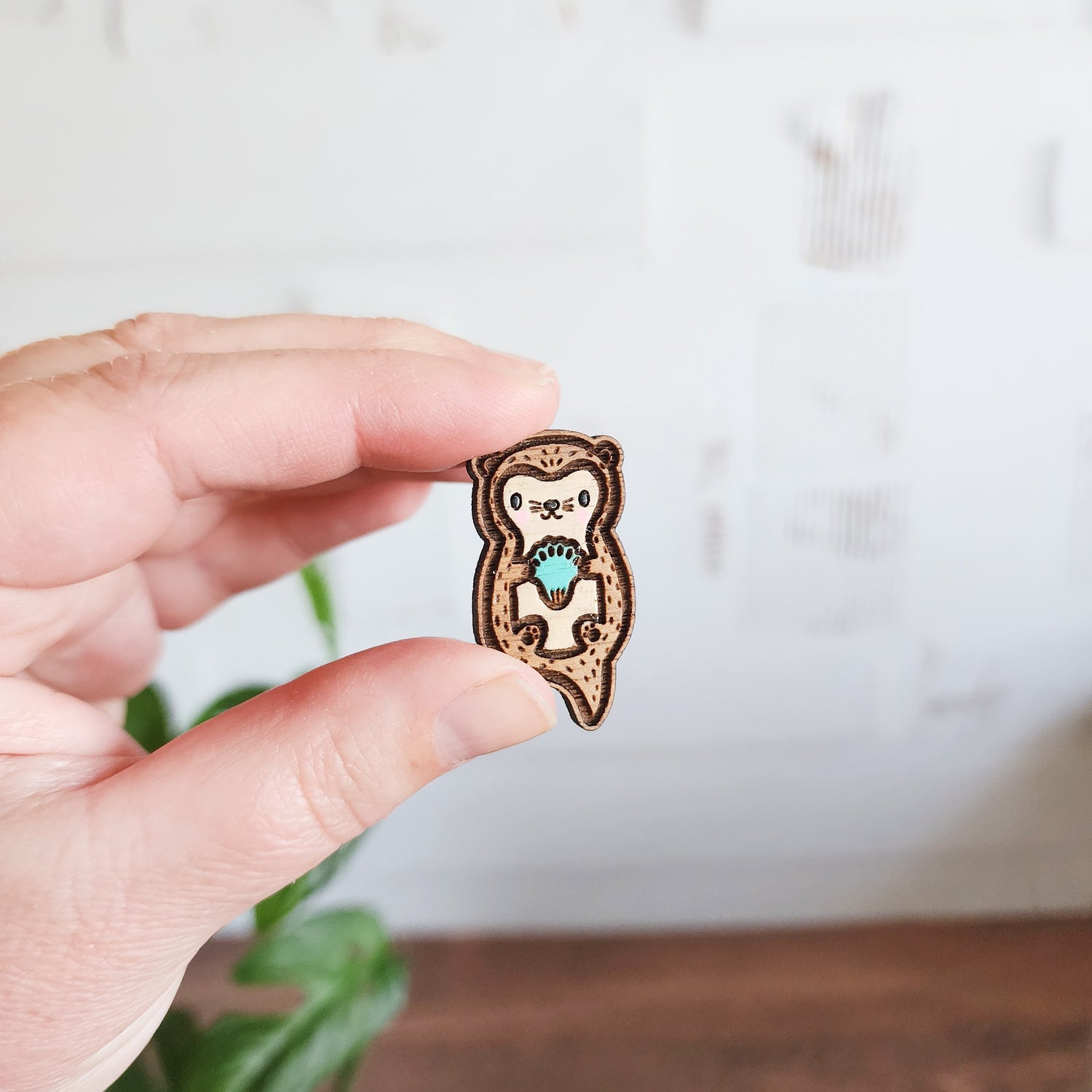 wooden otter pin held between two fingers