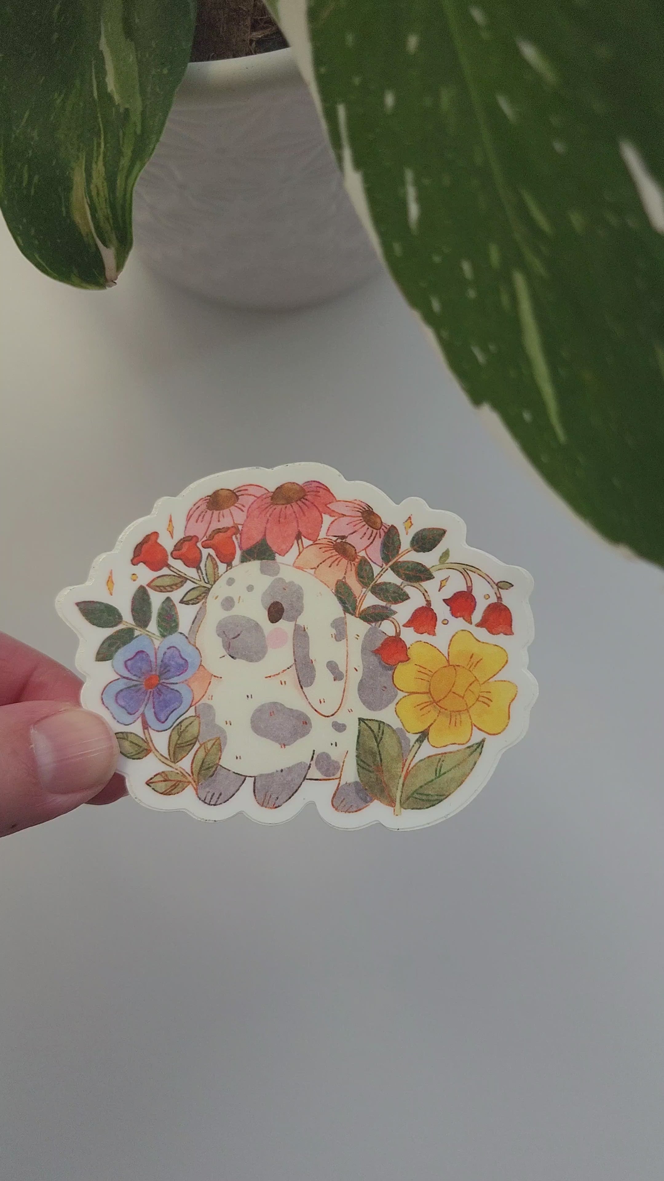 garden bunny sticker held in a hand next to a potted plant