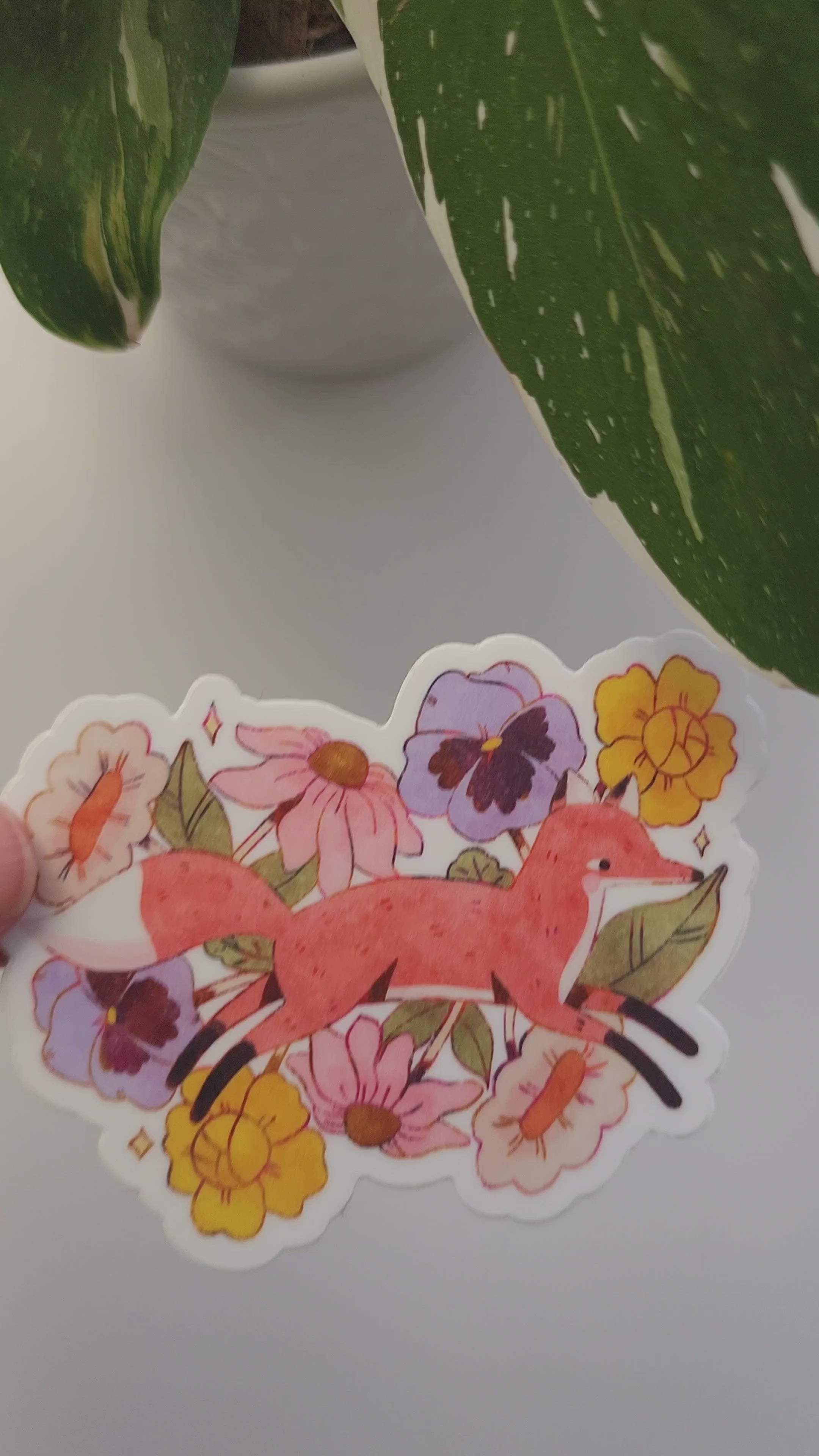 video of fox in blooms sticker held by a plant
