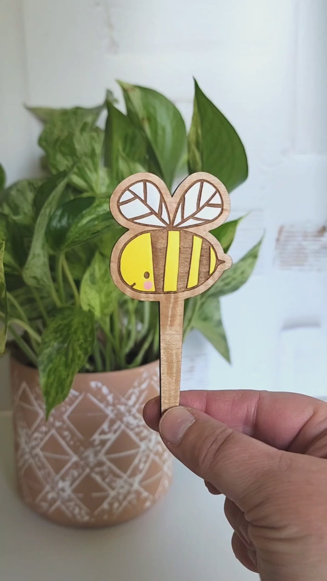 bee plant pick is rotated between front and back of design and then placed inside of a potted plant