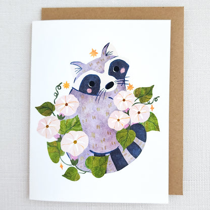Card with a raccoon illustration surrounded by flowers and leaves on a white background.